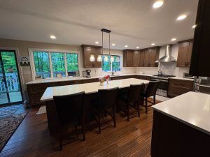 Contemporary kitchen with wood cabinets, white counters, and glass globe pendants