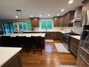 Wood cabinet kitchen with quartz counters, stainless hood, and long island