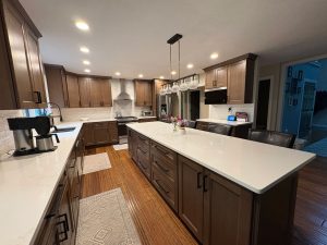 Natural wood kitchen with white countertops, long island, and pendant lights