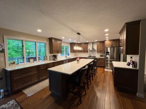 Bright remodeled kitchen with dark cabinets, long island, and pendant lights