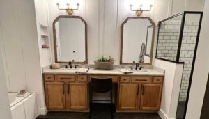 Double vanity bathroom with wood cabinetry and subway tile shower