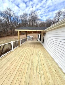 Wide backyard deck with gable roof porch and vinyl railing
