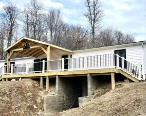 Raised backyard deck with white railing and covered gable roof