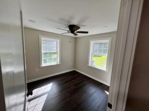 Brand new room added to room two bright windows dark ceiling fan dark wood floor